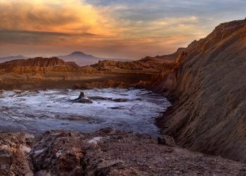 Tourists on a hilltop waiting for the sunset in the Valle de la Luna (Valley of the Moon) in the Atacama Desert, northern Chile, South America. The white areas on the valley floor are salt deposits.